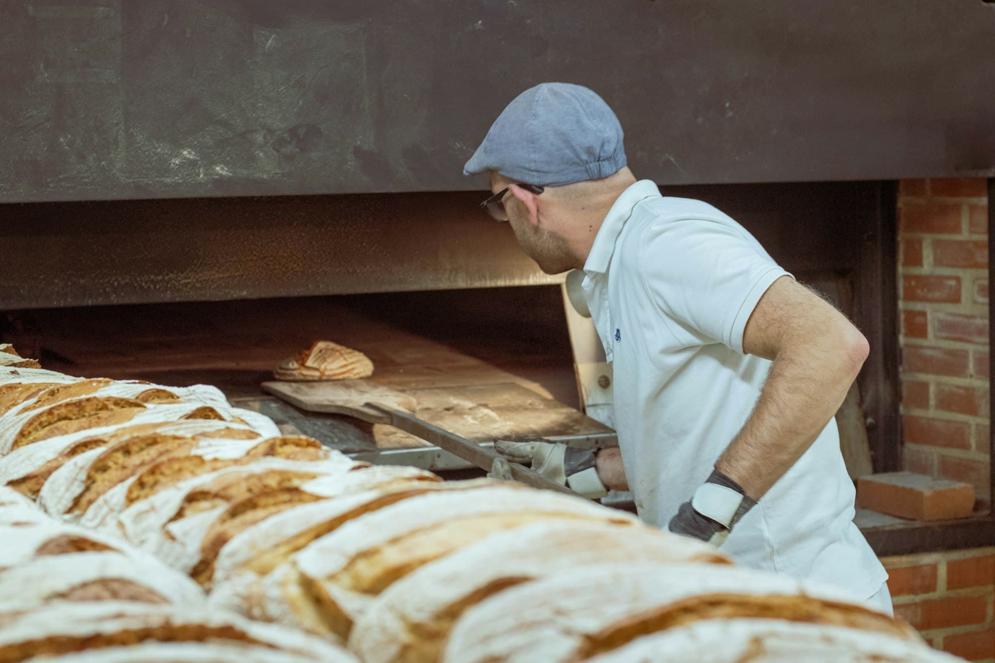 Un fornaio sforna il pane dal forno a legna